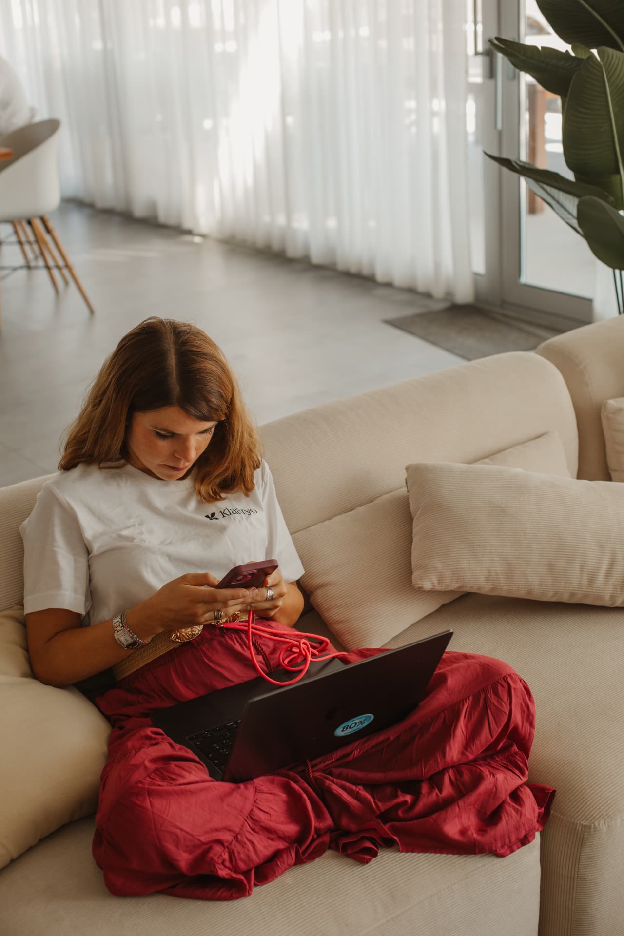 Collega Klaaryo lavora comodamente sul divano con laptop e smartphone